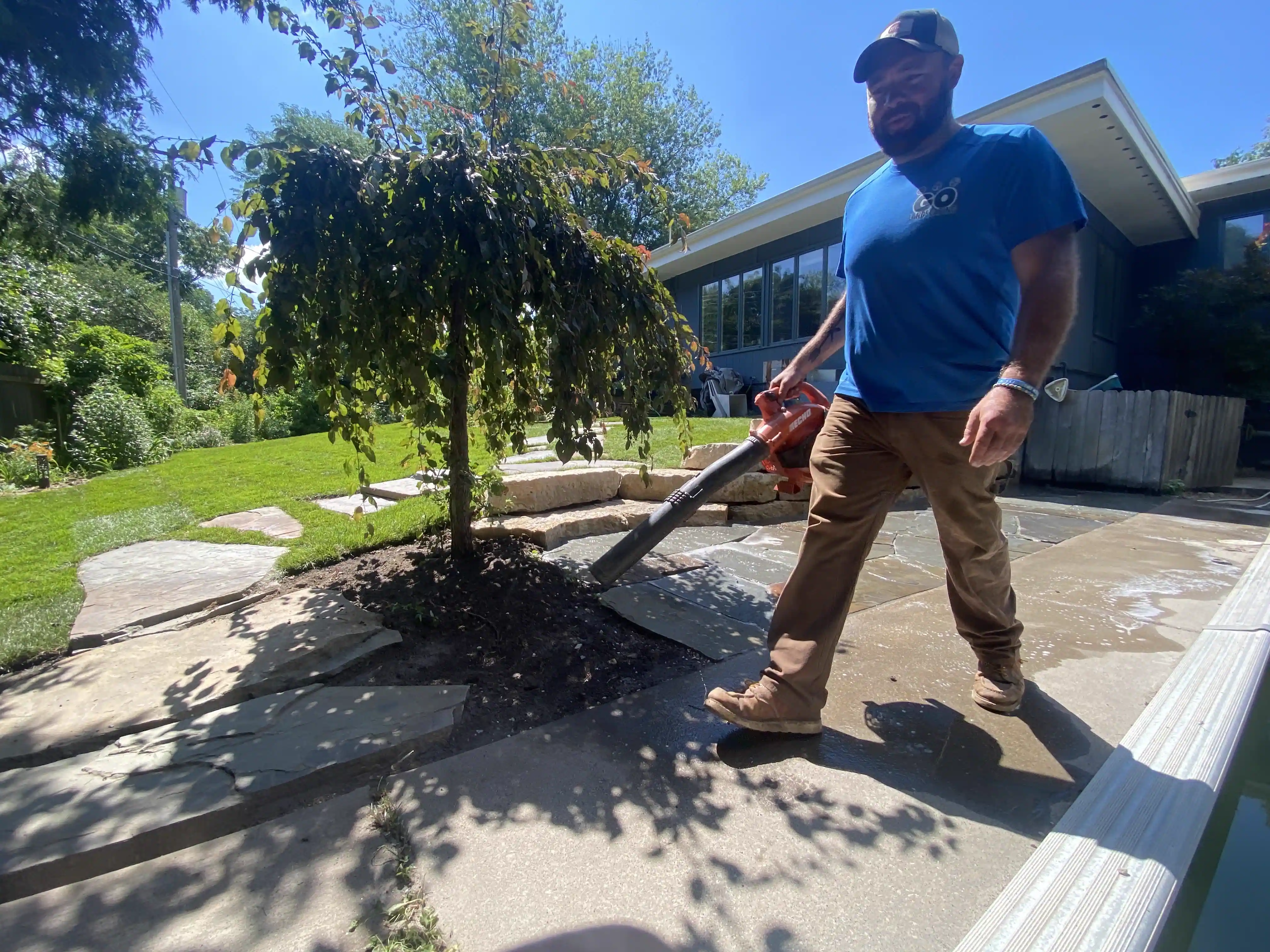 GO Landscaping crew member finishing a job site with a leaf blower