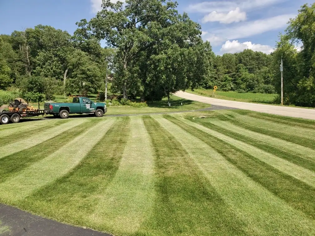 Freshly mowed lawn with crisp stripes and the GO Landscaping truck