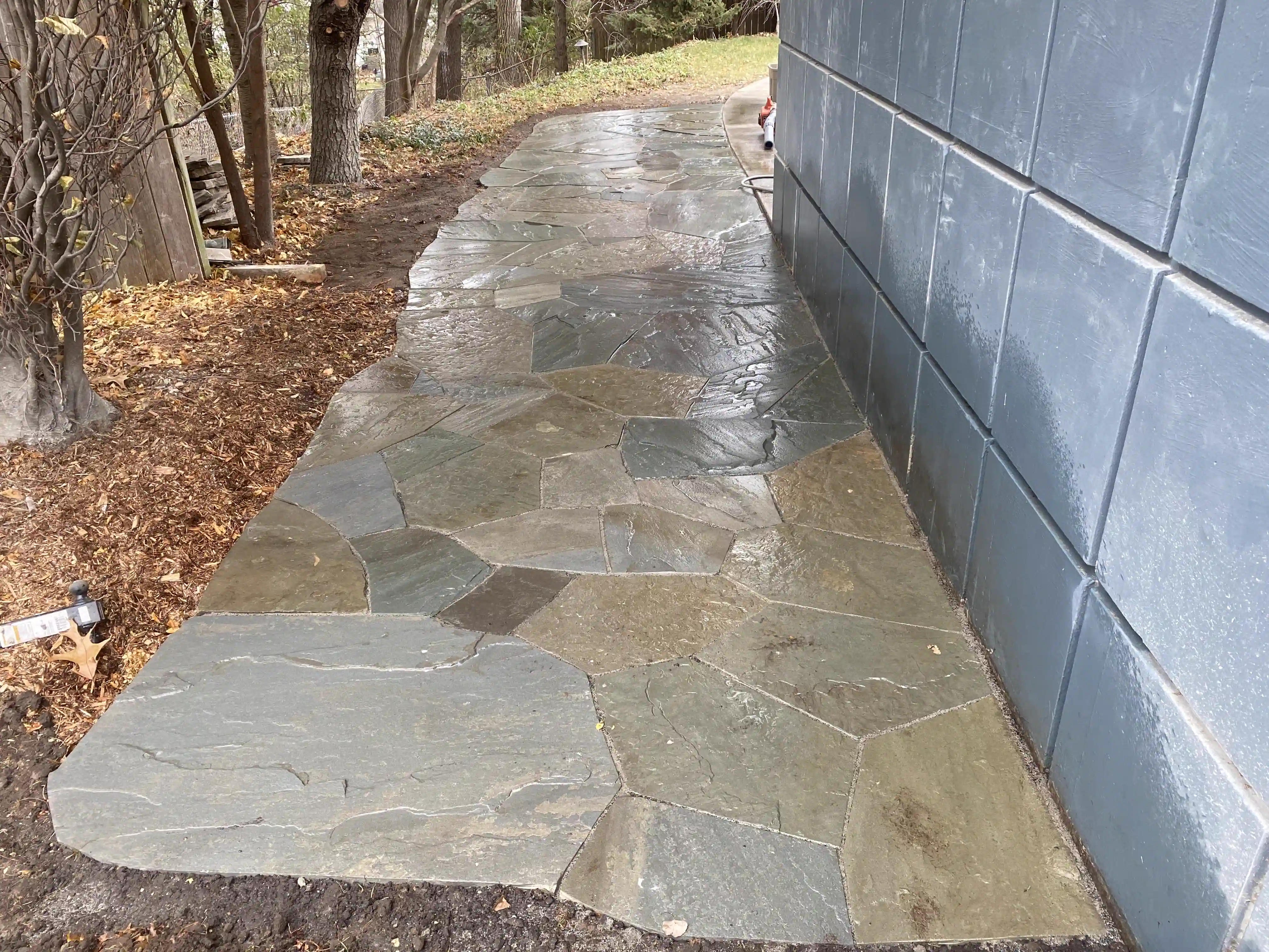 Flagstone walkway along a blue-sided home